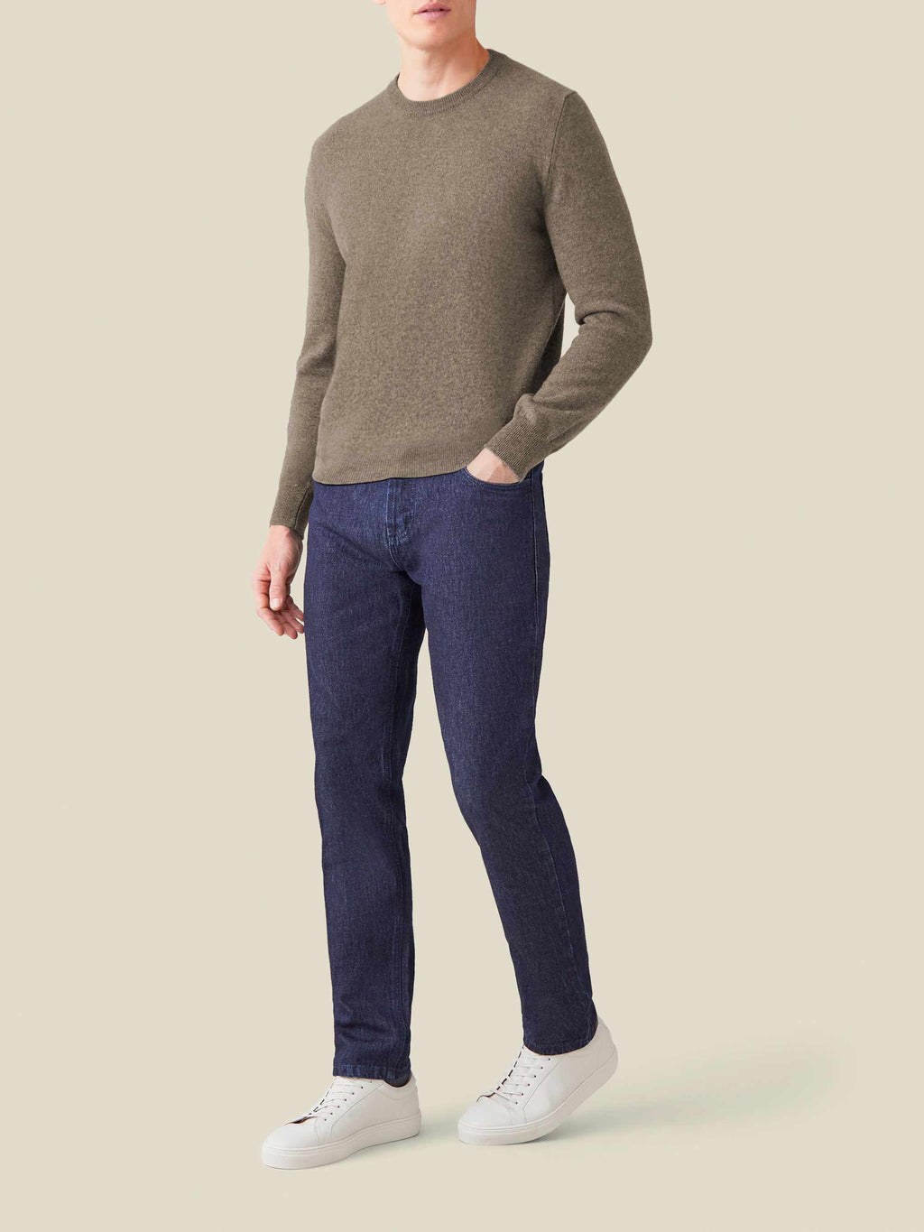 Full view of a model wearing the Nocciola Brown Cashmere Crew Neck with dark blue jeans and white sneakers.
