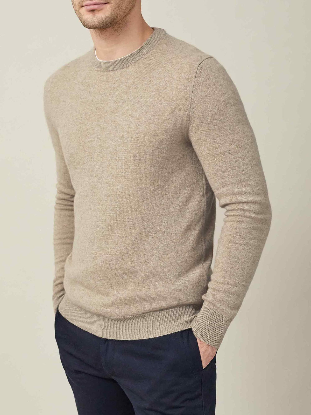 A man models the Luca Faloni pure cashmere crew neck sweater in camel beige against a plain background.