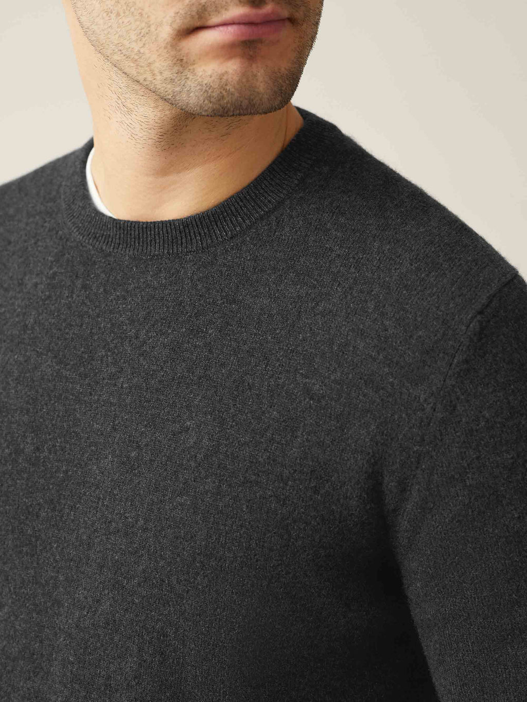 Close-up of a model wearing a Luca Faloni charcoal grey cashmere crew neck jumper, showing the texture and ribbed neckline.