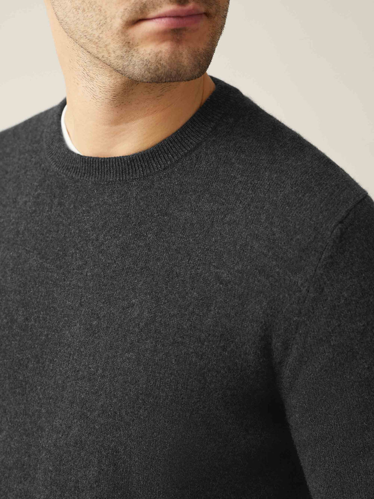 Close-up of a model wearing a Luca Faloni charcoal grey cashmere crew neck jumper, showing the texture and ribbed neckline.