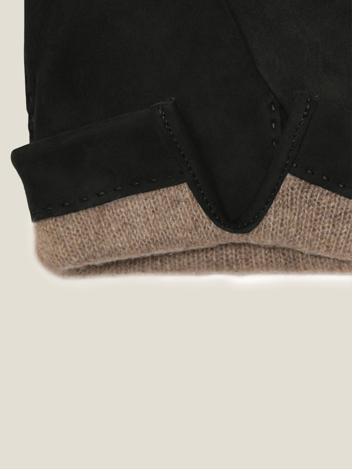 Detail of the cuff on the black nubuck leather gloves, highlighting the fine stitching and soft beige cashmere lining.