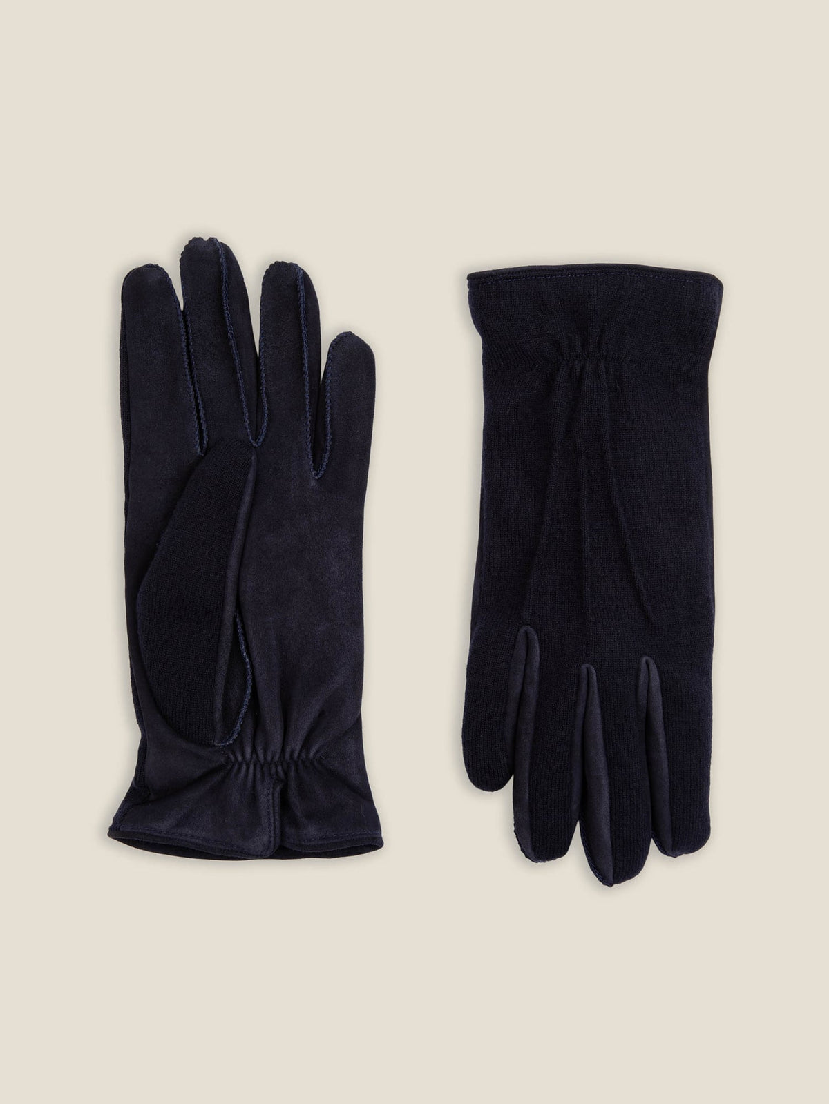 A pair of midnight blue cashmere and suede gloves laid flat, showing the suede palm and the cashmere back.