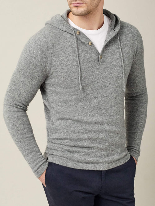 Front view of a model wearing the Luca Faloni pure cashmere hoodie in Dolomiti Grey over a white t-shirt and navy trousers.