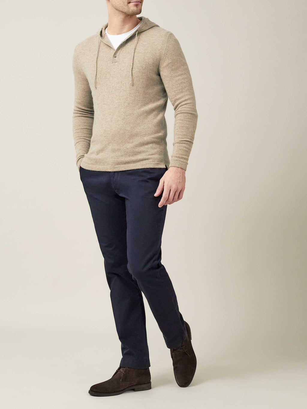A model wears the Luca Faloni Cashmere Hoodie in Camel Beige, styled with navy trousers and dark brown suede shoes.