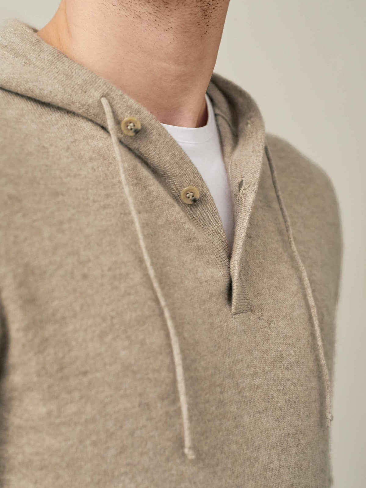 Close-up of the Luca Faloni cashmere hoodie in Camel Beige, showing the three-button placket, drawstrings, and hood detail.