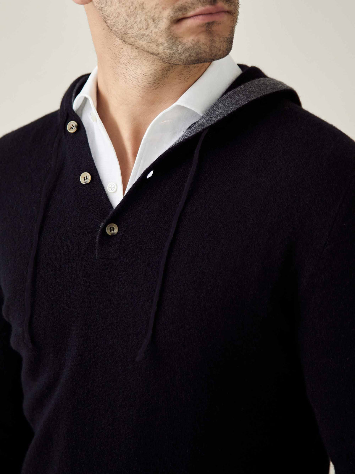 A close-up of the Luca Faloni Black Cashmere Hoodie, styled over a white shirt to showcase its three-button placket.