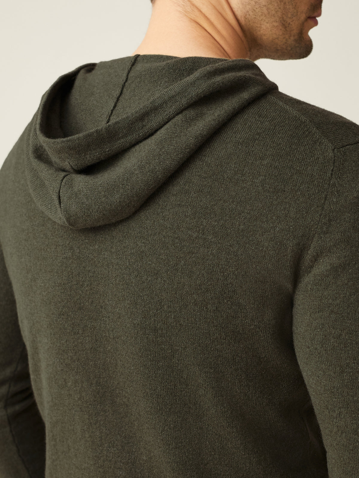 Close-up of the back of a man wearing the Hunting Green Cashmere Hoodie, showing the hood and knit texture.