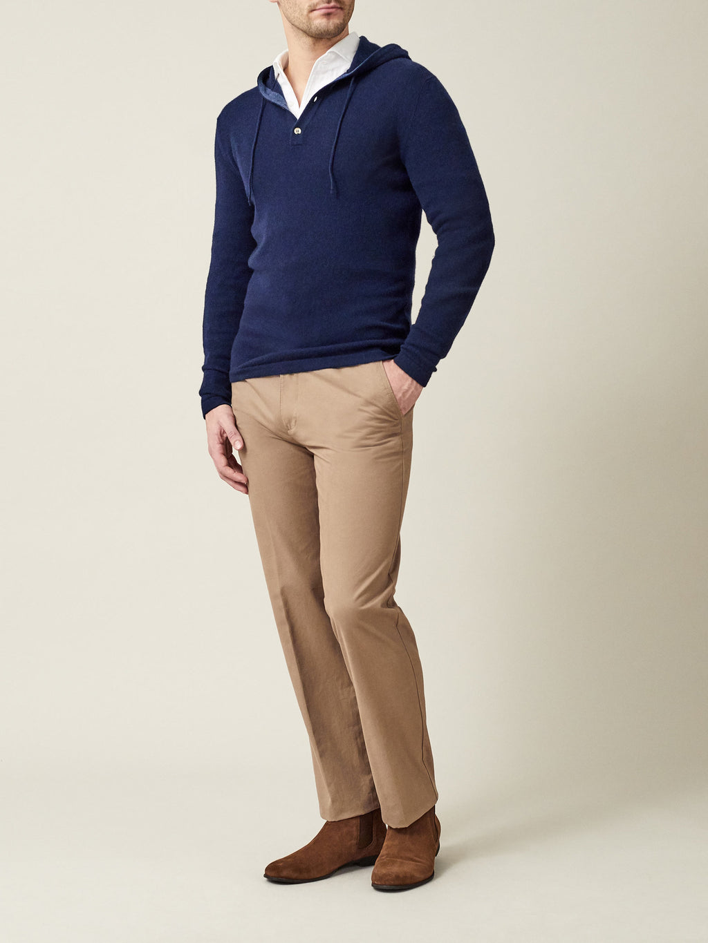 A model wears the Luca Faloni Navy Blue Cashmere Hoodie over a white shirt, paired with beige chinos and brown suede boots.