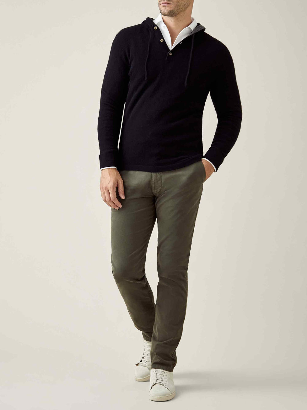 A model wears the Luca Faloni Black Cashmere Hoodie, layered over a white shirt with olive chinos and white sneakers.