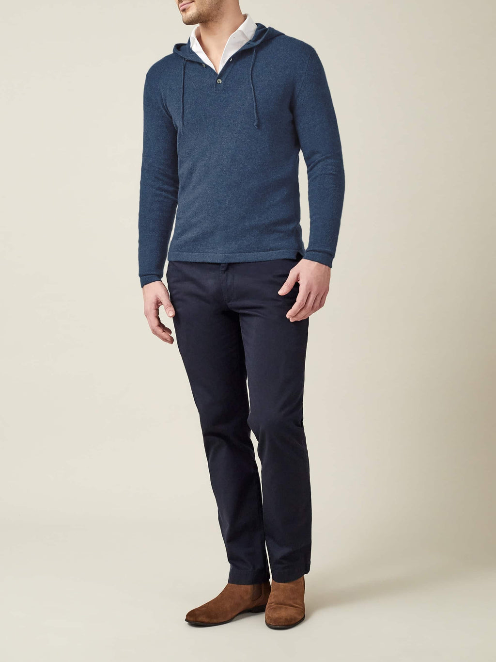 A man models the Luca Faloni Pure Cashmere Hoodie in Atlantic Blue, styled with a white shirt, dark trousers, and boots.