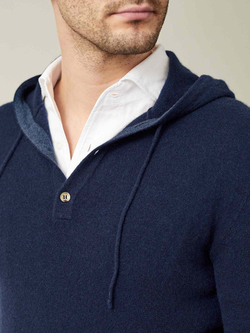 Close-up of the Luca Faloni navy blue cashmere hoodie's button placket and hood, styled on a model over a white shirt.