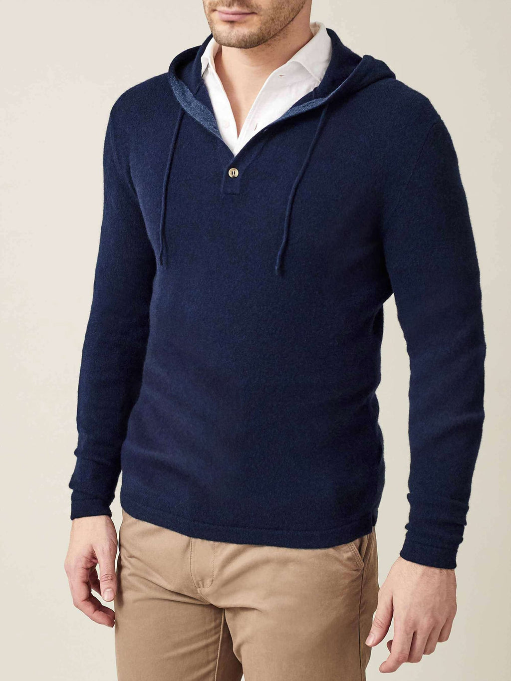 A model wears the Luca Faloni navy blue pure cashmere hoodie layered over a white shirt and paired with beige chinos.