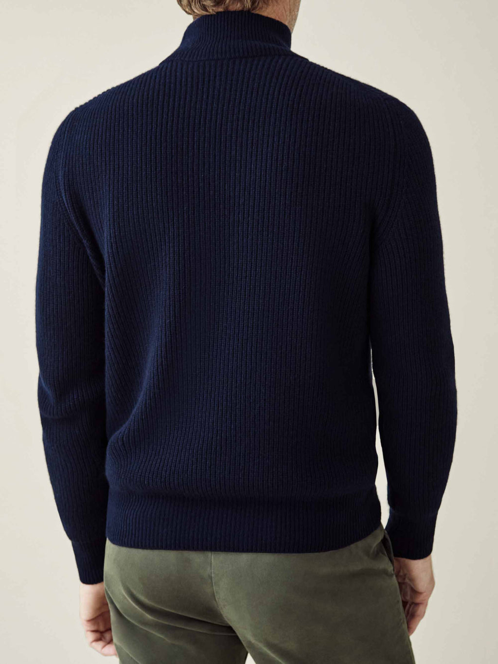 Back view of a man wearing a midnight blue chunky knit cashmere mock neck, showing the ribbed texture and relaxed fit.