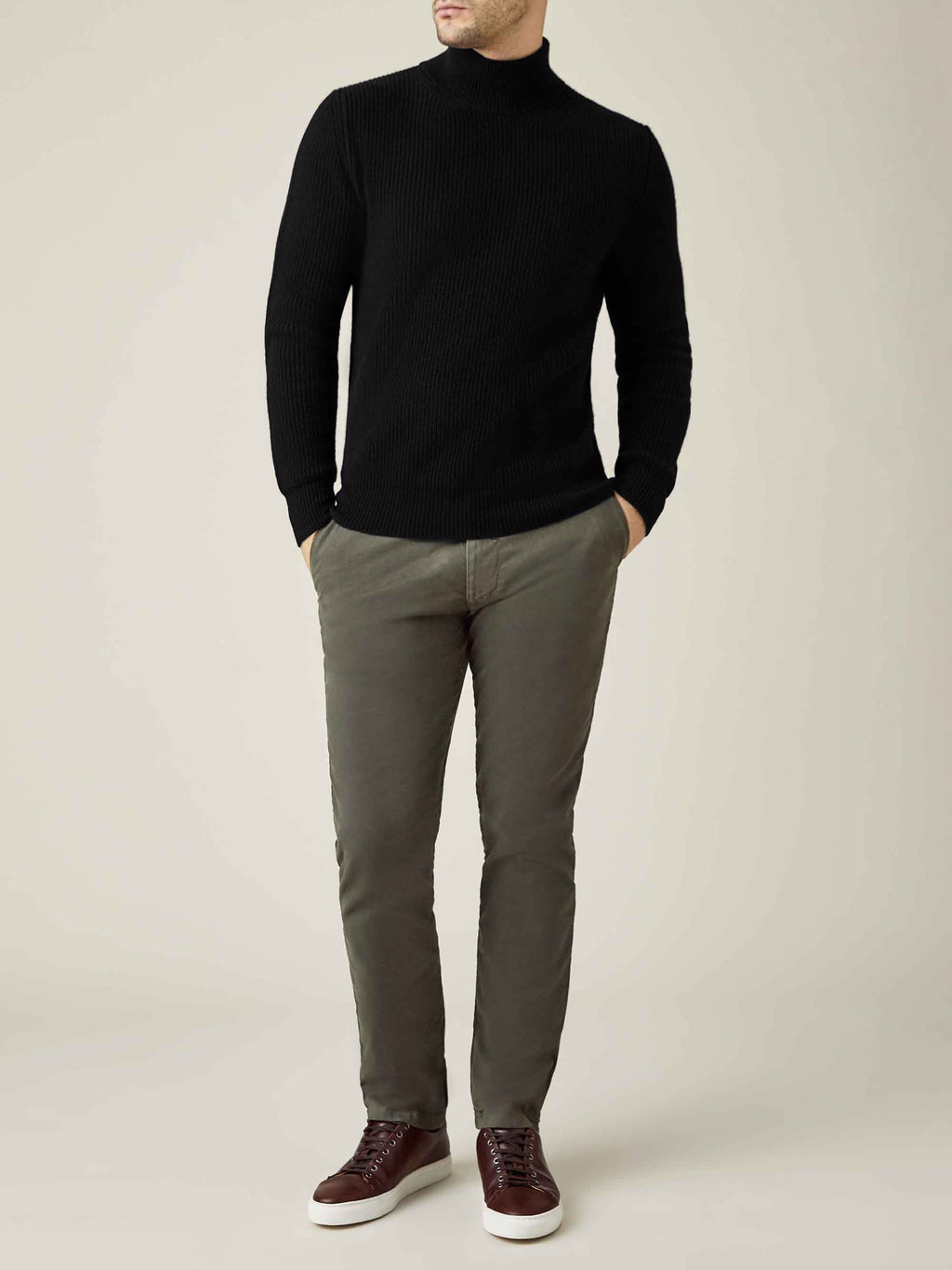 Model wears the Black Chunky Knit Cashmere Mock Neck, styled with olive trousers and brown leather trainers.