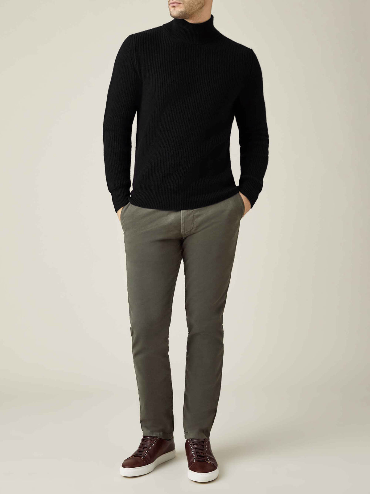 Model wears the Black Chunky Knit Cashmere Mock Neck, styled with olive trousers and brown leather trainers.