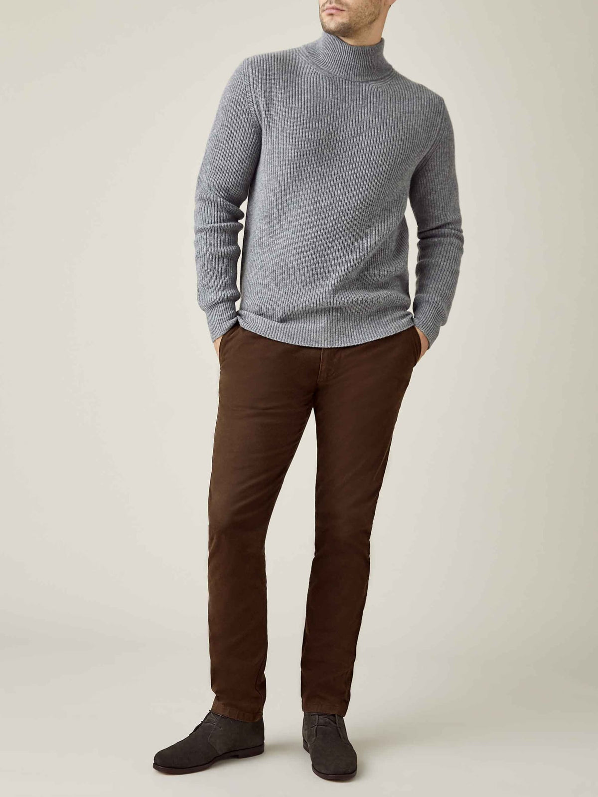 A full-length view of a model wearing the Luca Faloni Chunky Knit Cashmere Mock Neck in Dolomiti Grey with brown trousers.