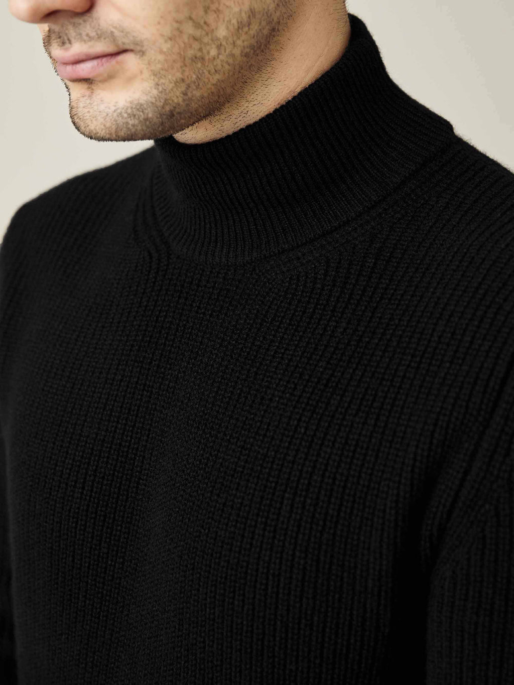 Close-up of a man wearing the black Chunky Knit Cashmere Mock Neck, showing the detail of the ribbed knit and high collar.