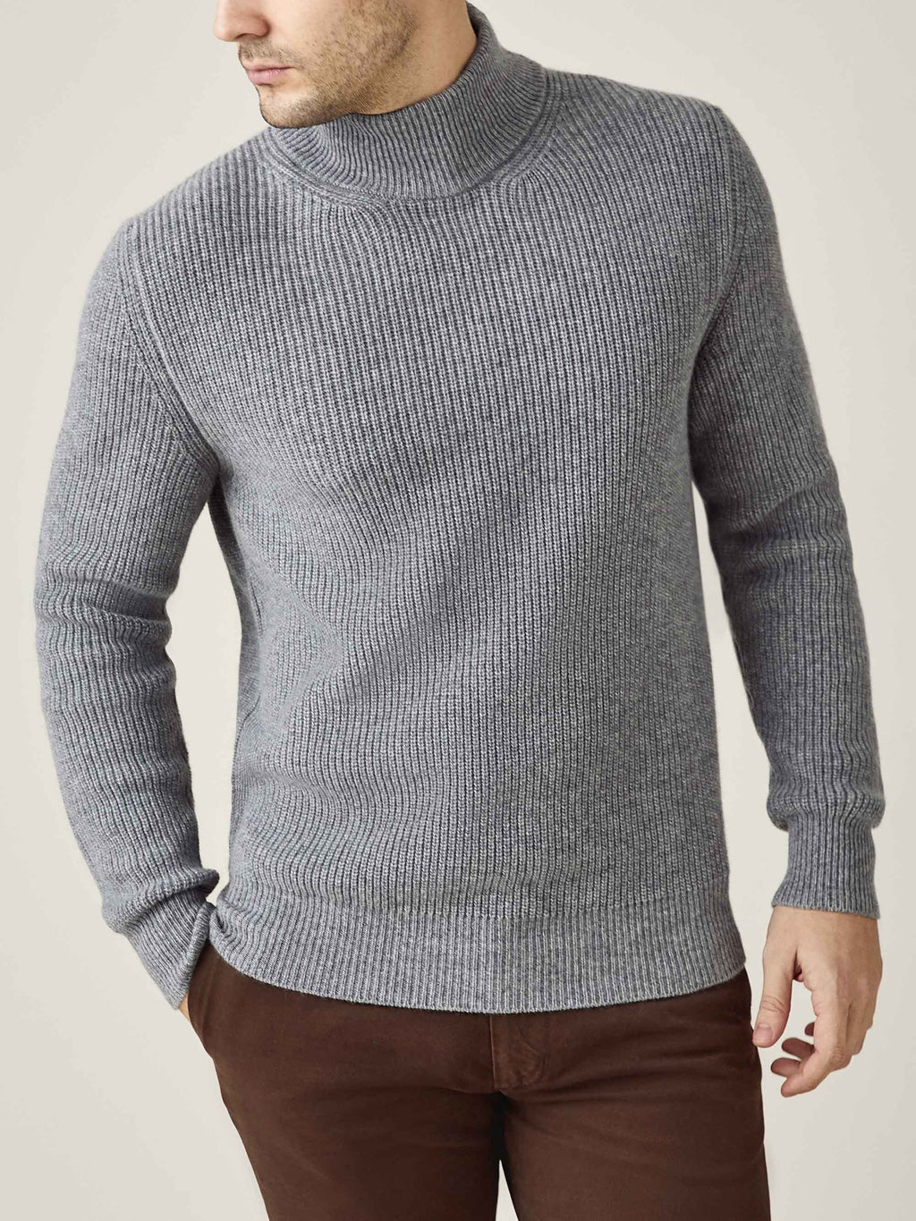 A model wears the Chunky Knit Mock Neck in Dolomiti Grey, showcasing the sweater's ribbed texture and relaxed silhouette.