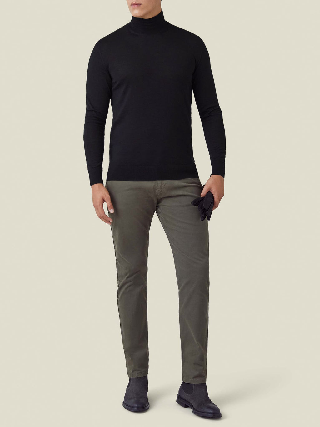 A model wears the Luca Faloni Black Silk-Cashmere Mock Neck, paired with dark olive chinos and black Chelsea boots.
