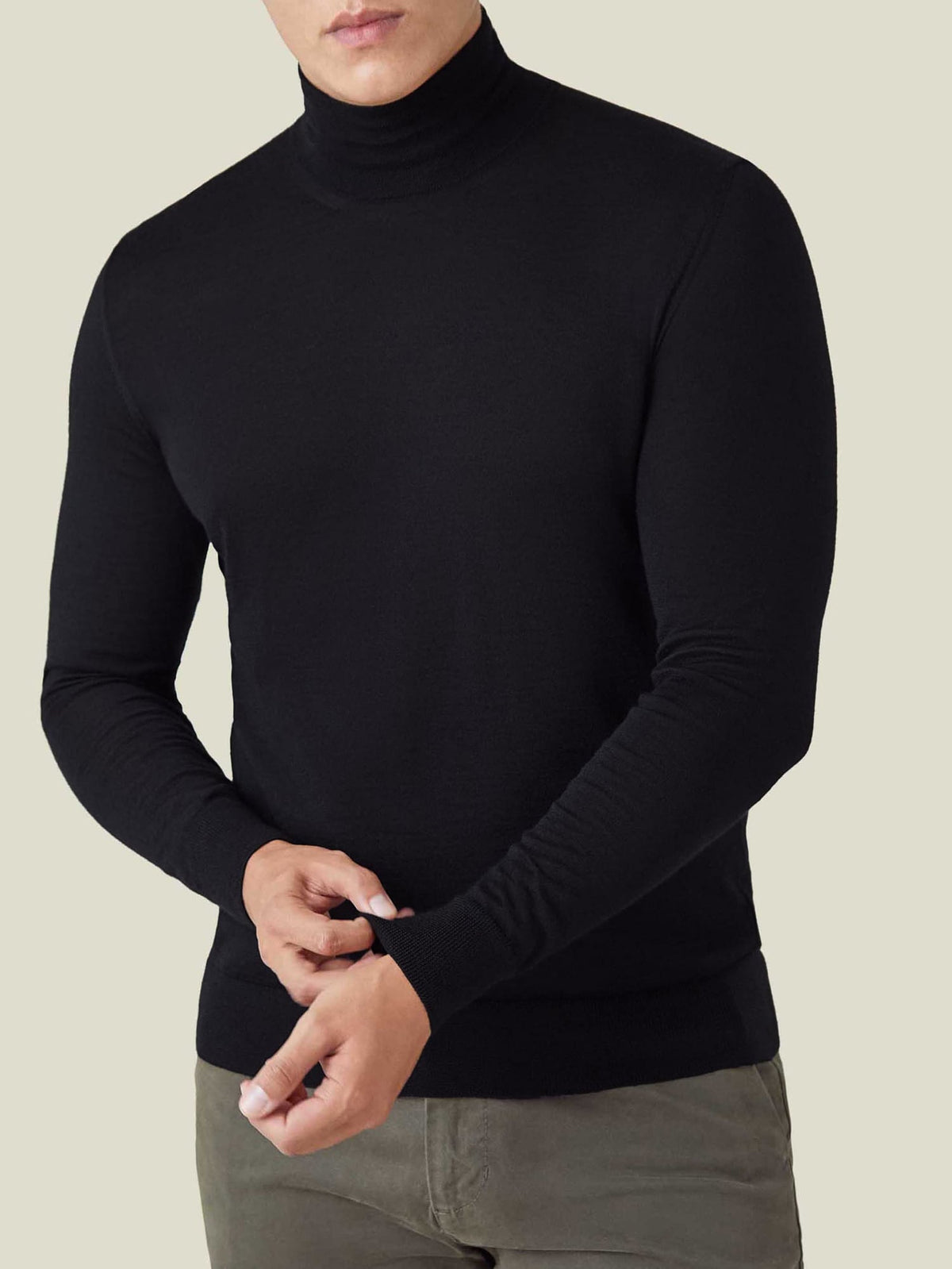 Front view of a model wearing the Luca Faloni Black Silk-Cashmere Mock Neck while adjusting the ribbed cuff.