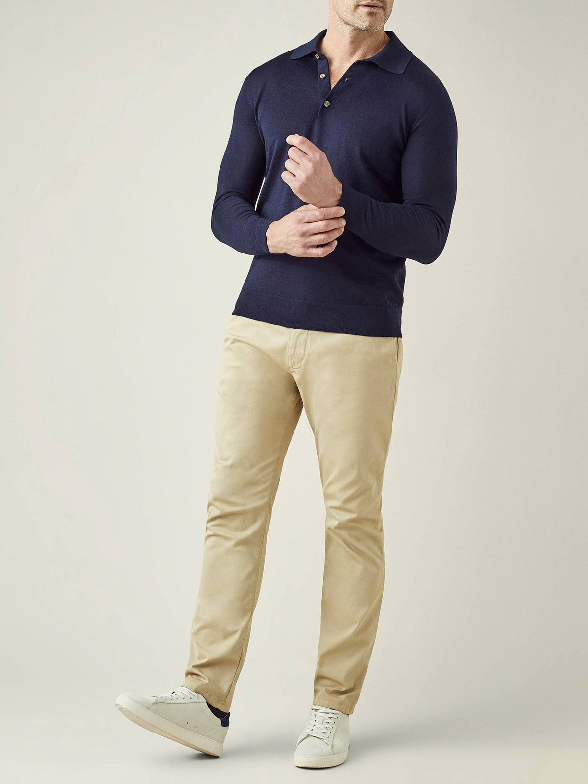 Full-length shot of a man wearing the navy blue Fine Silk Cashmere Polo with beige chinos and white sneakers.