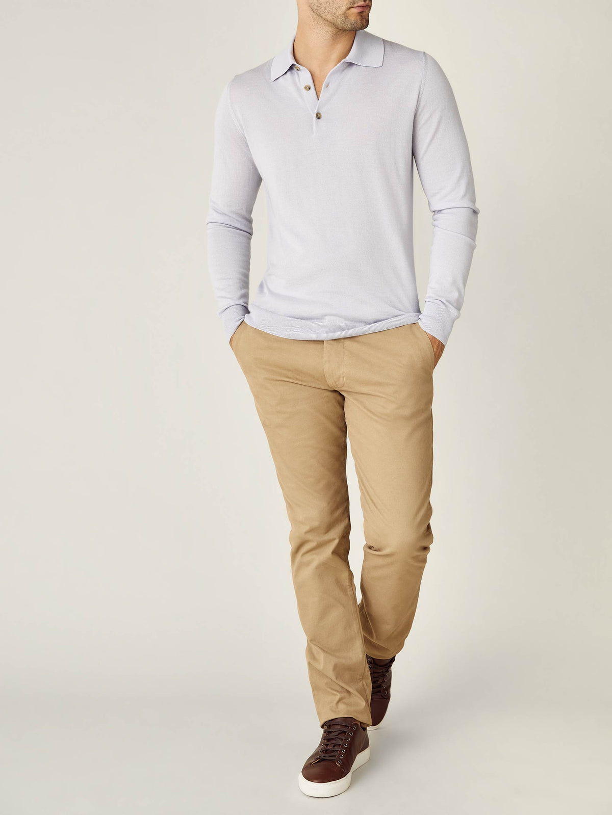 A model wearing the Luca Faloni Fine Silk Cashmere Polo in Ice Grey, paired with tan chinos and brown sneakers.