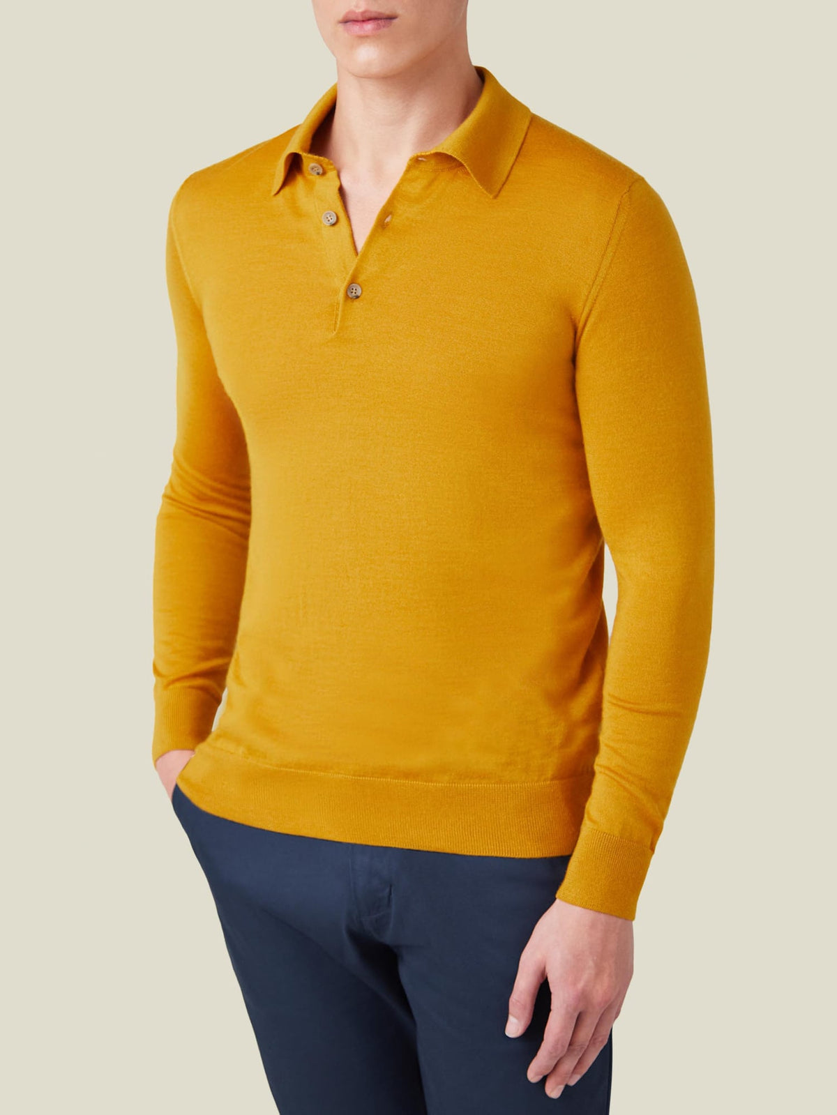 Front view of a model wearing the Fine Silk Cashmere Polo in Mustard with dark blue trousers.