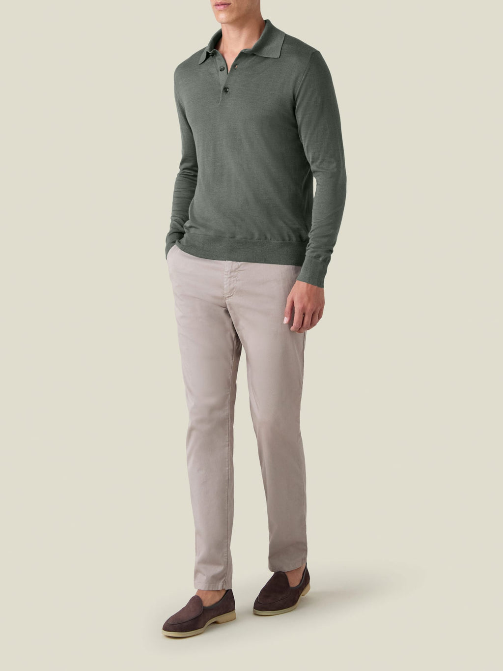 Three-quarter view of a man wearing the Moss Green Fine Silk Cashmere Polo with light-coloured trousers and brown loafers.