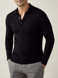 Front view of a model wearing the black long-sleeved Fine Silk Cashmere Polo paired with grey trousers.