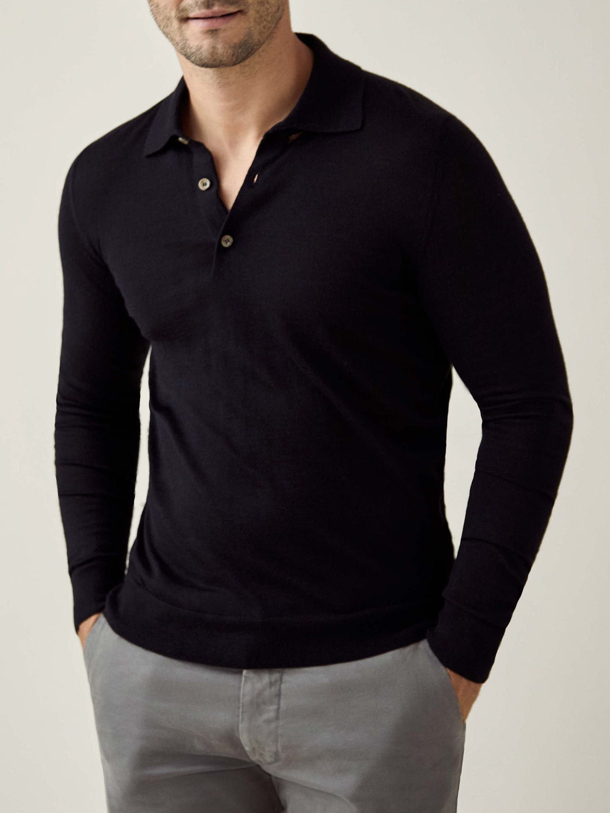 Front view of a model wearing the black long-sleeved Fine Silk Cashmere Polo paired with grey trousers.