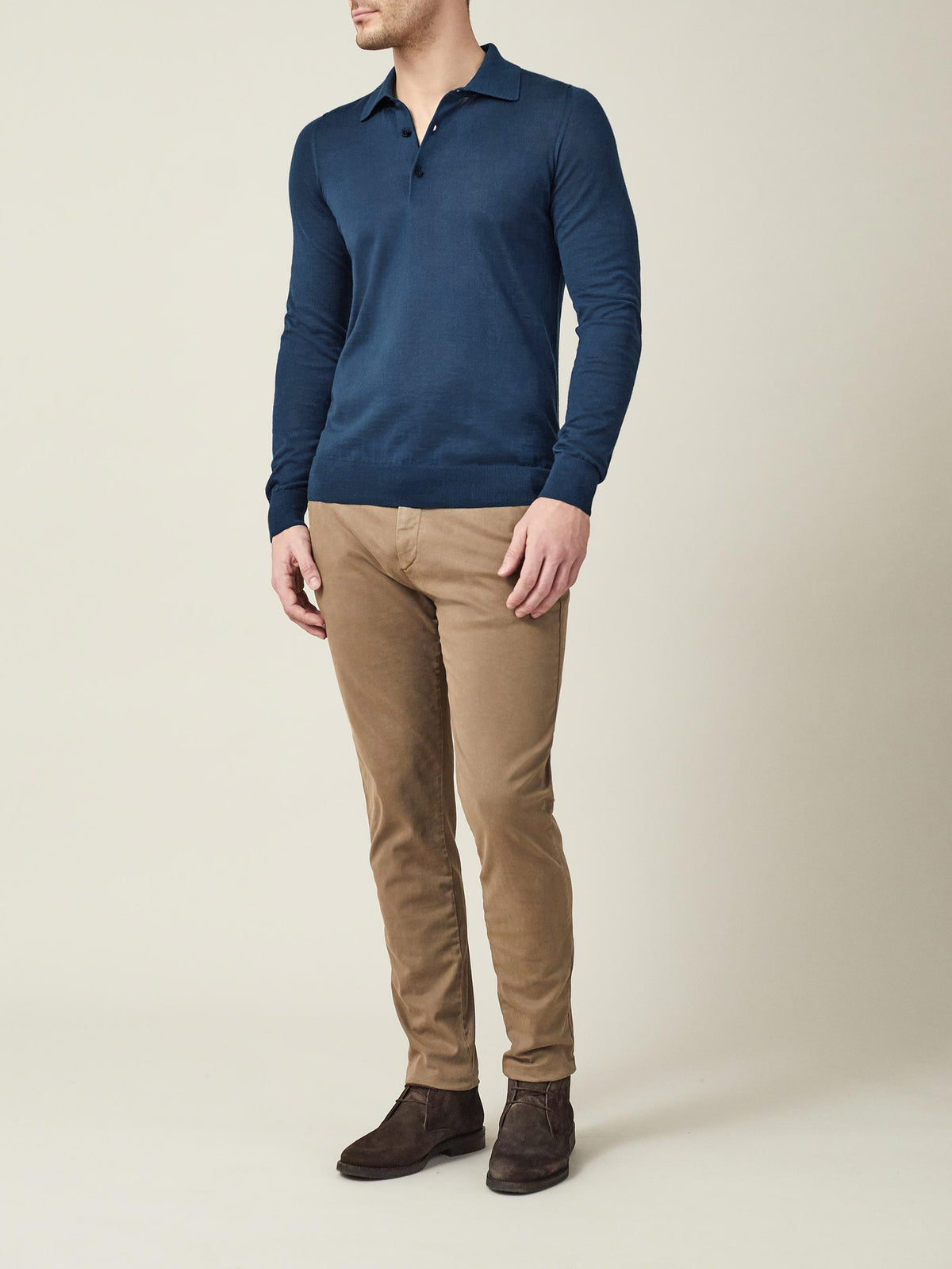 A model wearing the long-sleeved Fine Silk Cashmere Polo in Atlantic Blue with tan trousers and brown suede boots.
