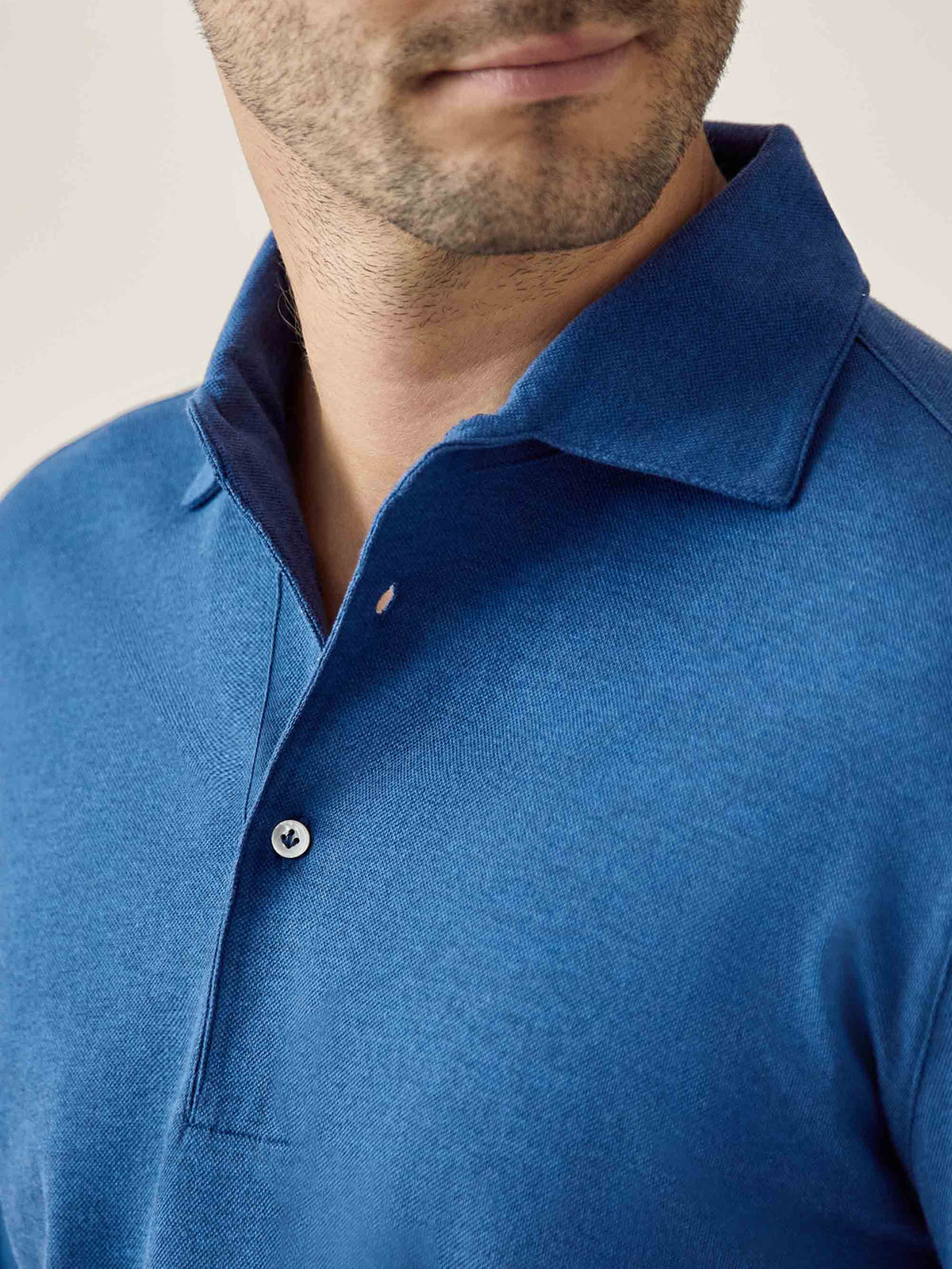 Close-up detail of the Brera Piqué Polo Shirt in royal blue, highlighting the one-piece collar and mother-of-pearl button.