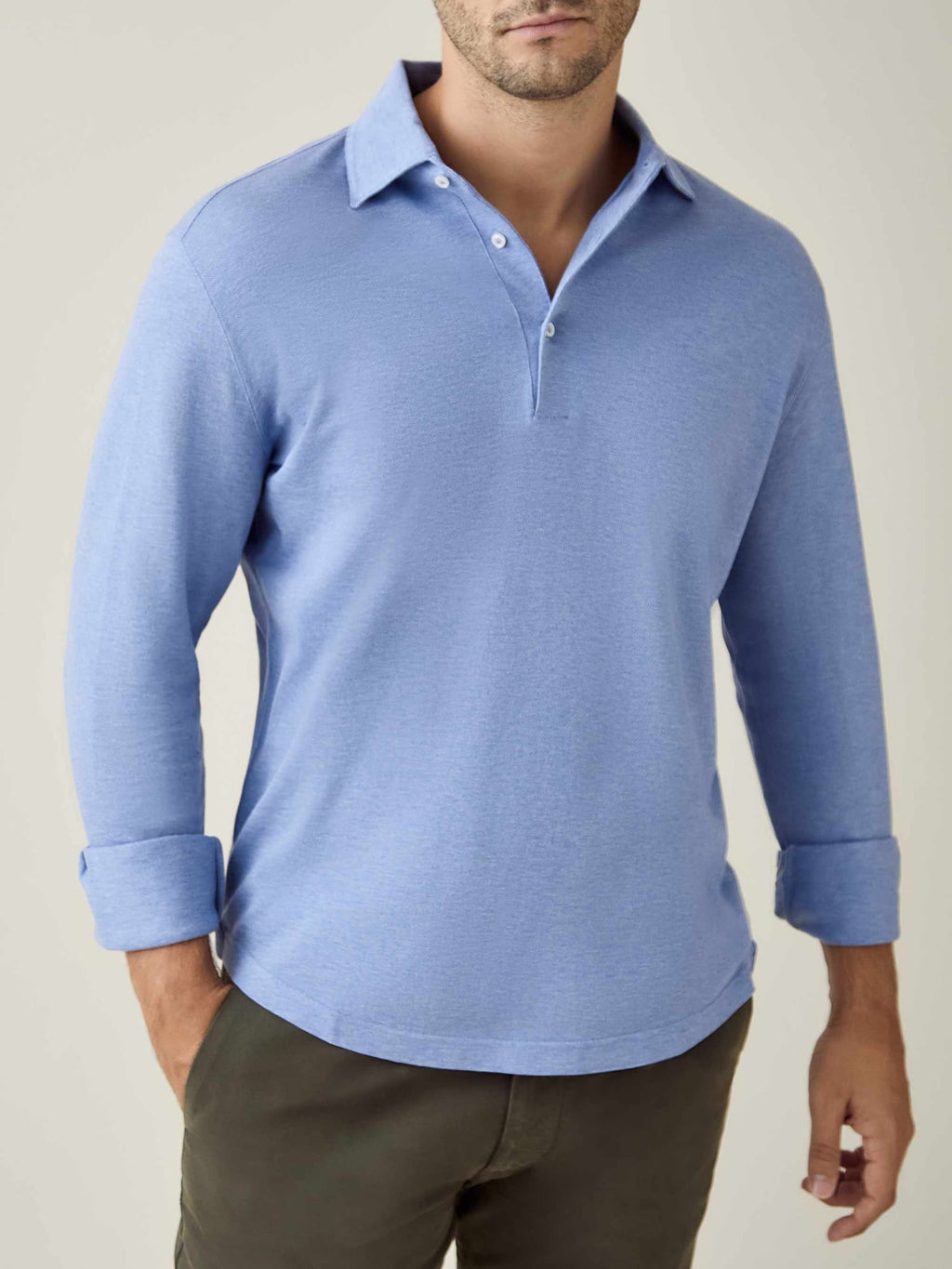 A man wearing the light blue long-sleeved Brera Piqué Polo Shirt with the sleeves rolled up.