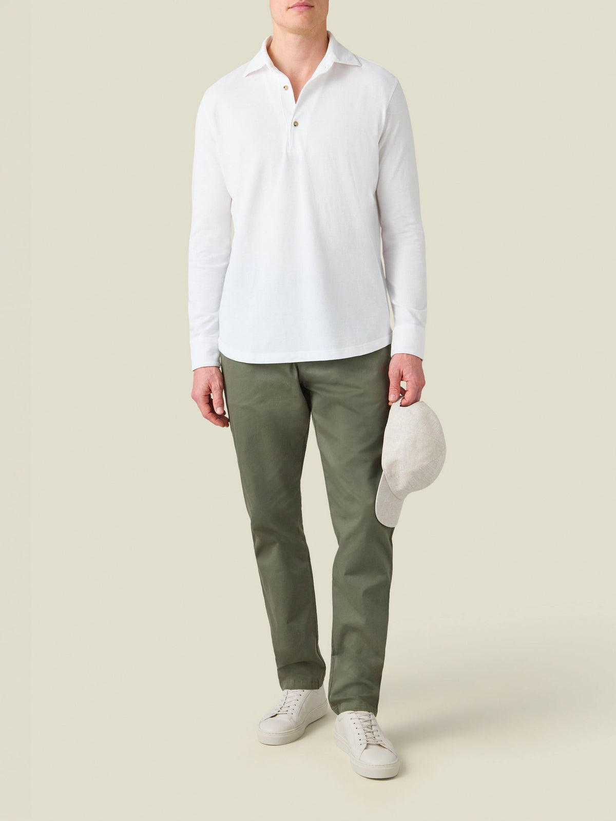 Full-length view of a model wearing the white Brera Piqué Polo Shirt with green chinos and white sneakers.