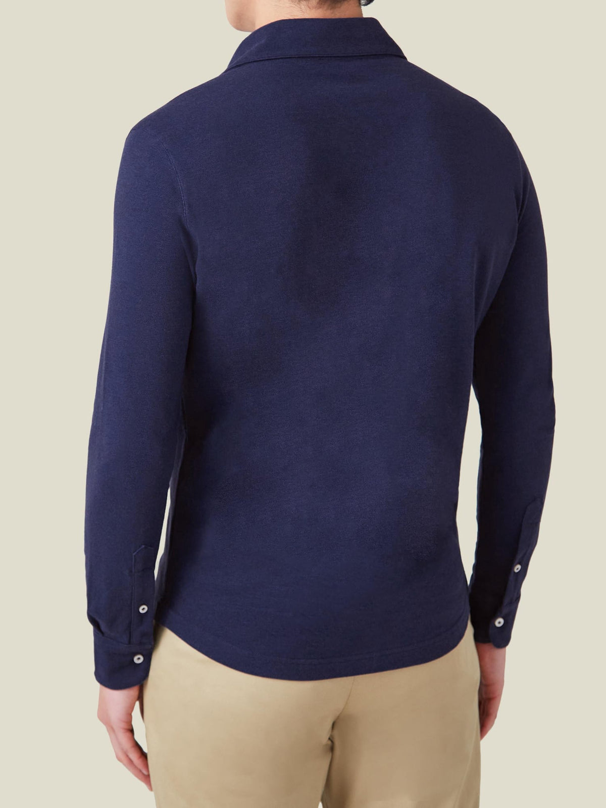 Back view of a man wearing the navy blue Brera Piqué Polo Shirt with long sleeves and shirt cuffs.