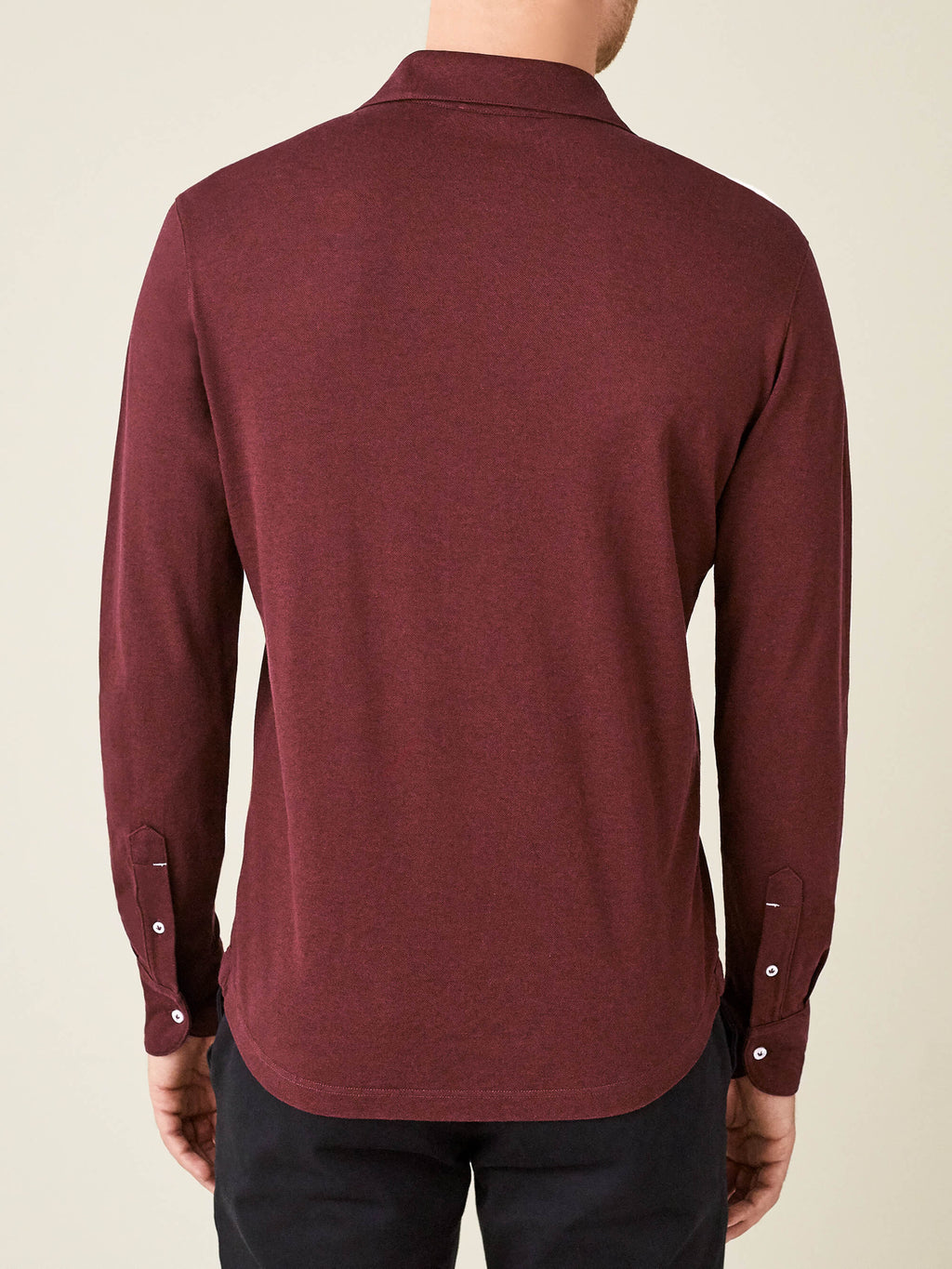 Back view of a model wearing the Brera Piqué Polo Shirt in lava red, showcasing the relaxed fit and shirt-style cuffs.
