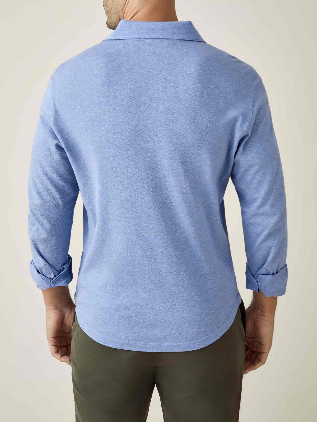 Back of a model wearing the light blue Brera Piqué Polo Shirt. The long sleeves are rolled up to reveal the shirt cuffs.