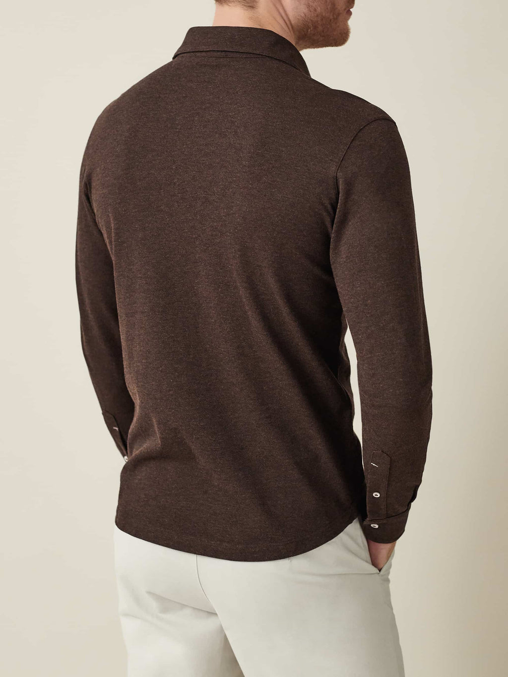 Back view of a model wearing the Brera Piqué Polo Shirt in Chocolate Brown, paired with light-coloured chinos.