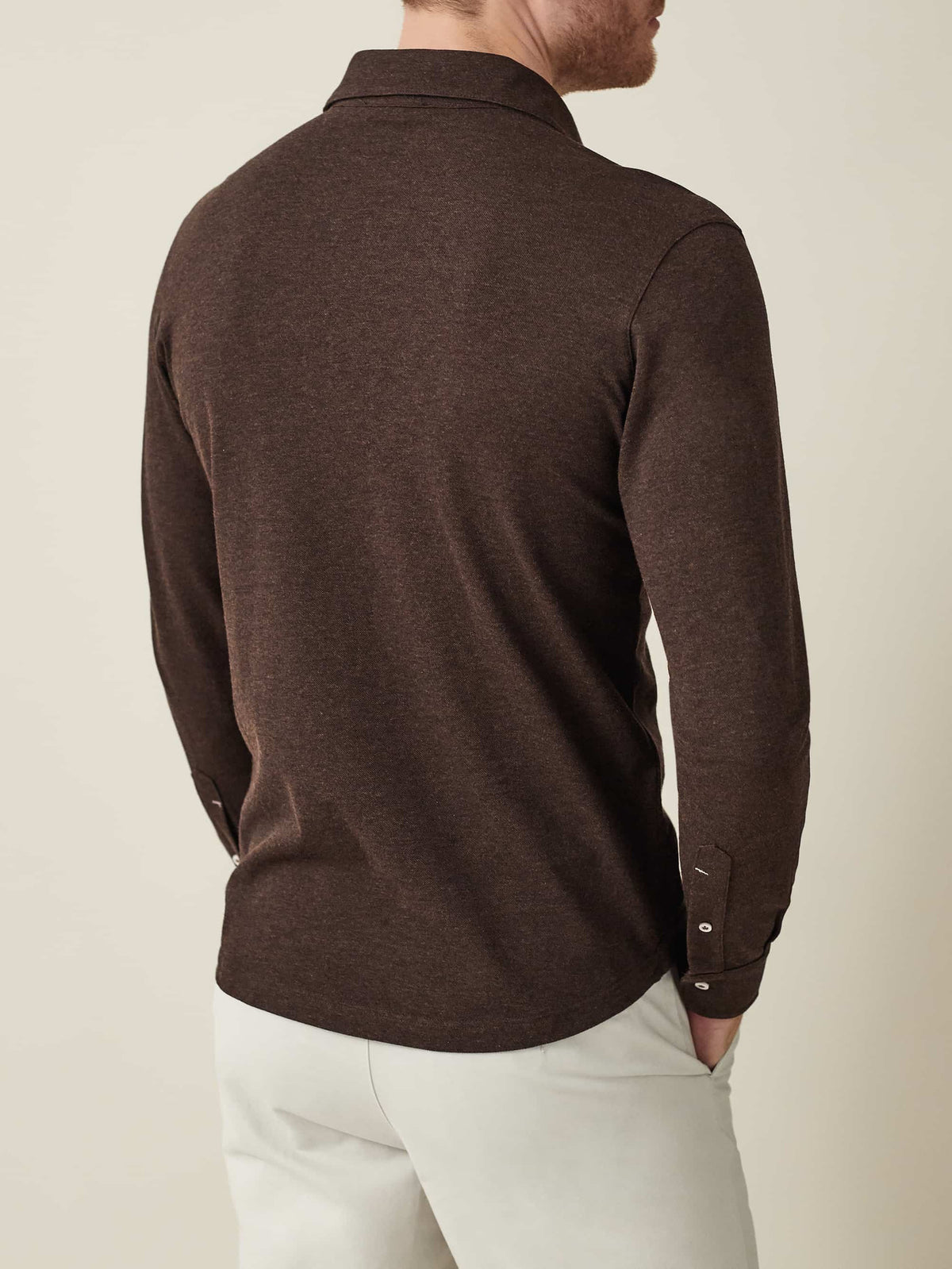 Back view of a model wearing the Brera Piqué Polo Shirt in Chocolate Brown, paired with light-coloured chinos.