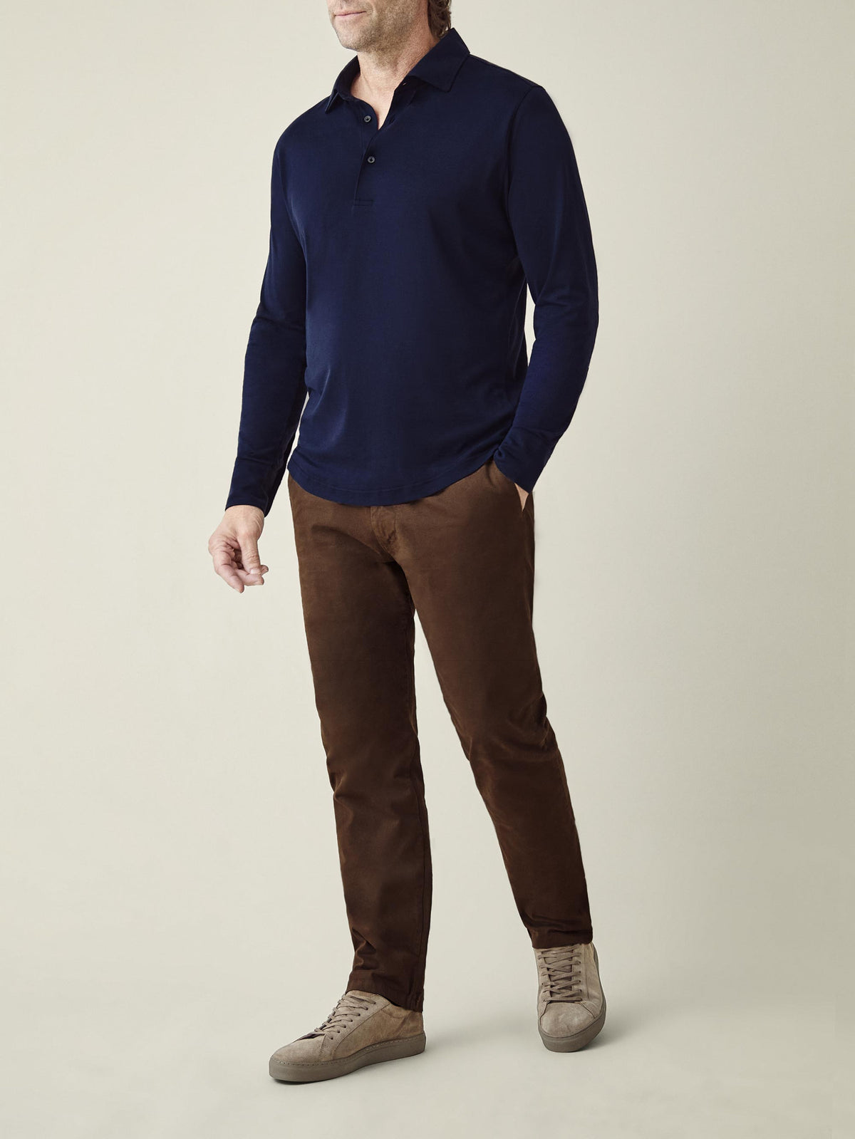 Full-body shot of a model wearing the Amalfi Silk-Cotton Polo Shirt in Midnight Blue, paired with brown trousers.