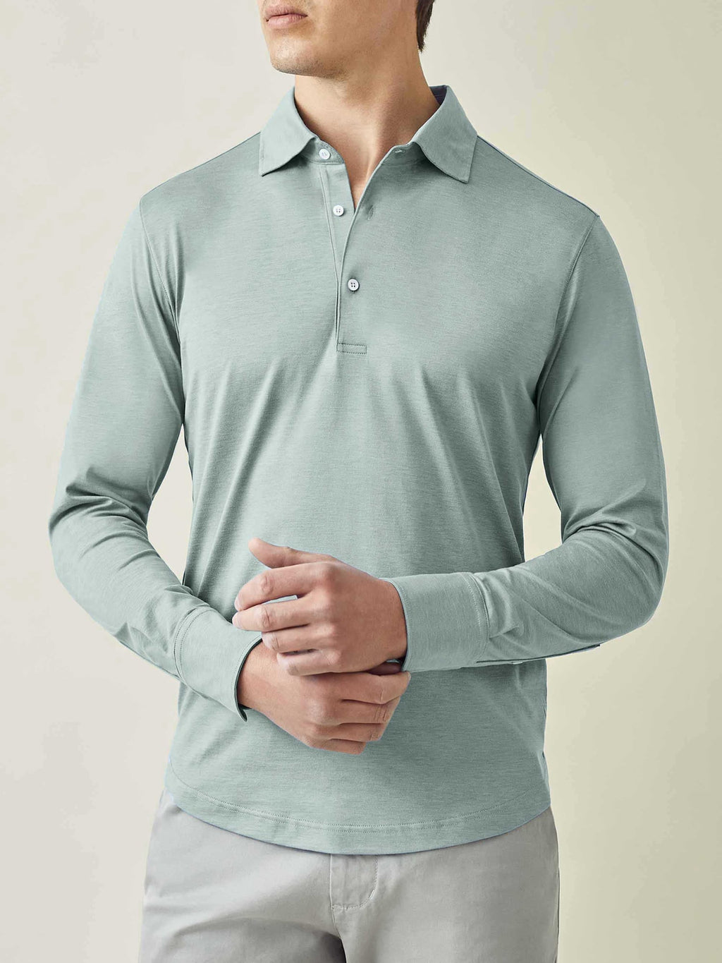 Model from the waist up wearing the long-sleeved Amalfi Silk-Cotton Polo Shirt in Marine Green against a studio backdrop.