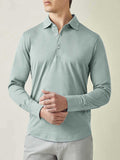 Model from the waist up wearing the long-sleeved Amalfi Silk-Cotton Polo Shirt in Marine Green against a studio backdrop.