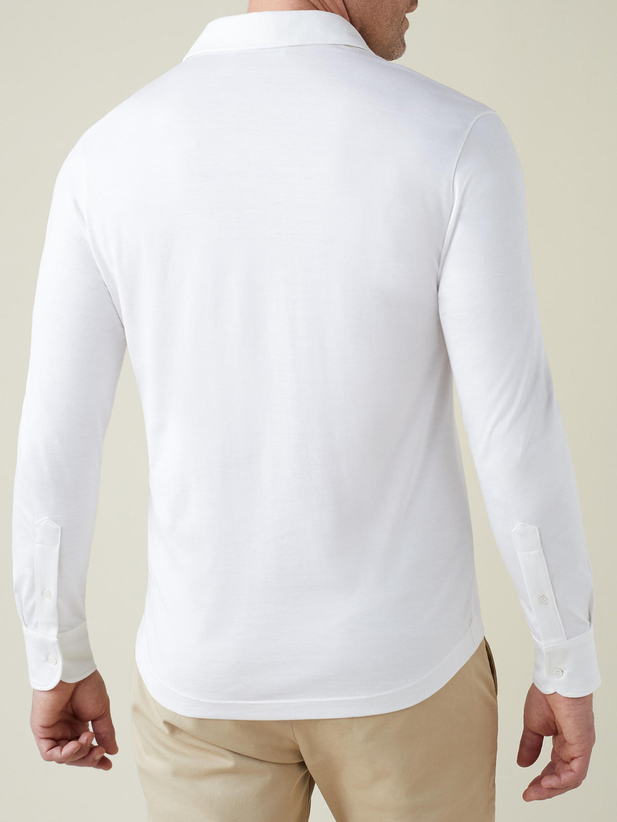 Back view of a man wearing the white Amalfi Silk-Cotton Polo Shirt, showing its fit and classic shirt cuffs.