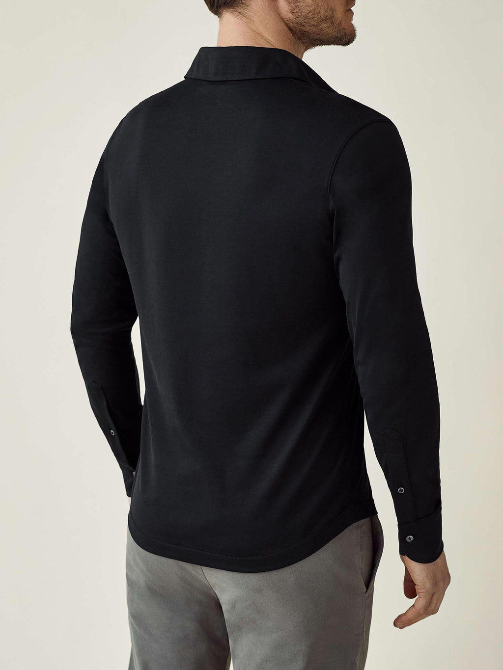 Rear view of a model wearing the black Amalfi Silk-Cotton long-sleeved polo shirt.