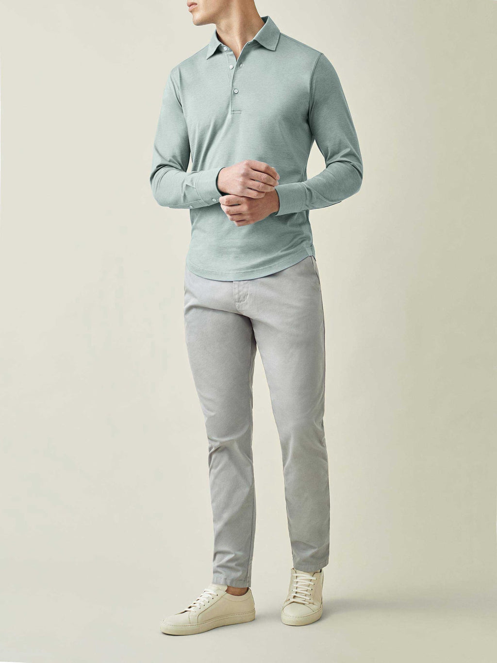 Full length view of a model wearing the Amalfi Silk-Cotton Polo Shirt in Marine Green with light grey trousers and sneakers.