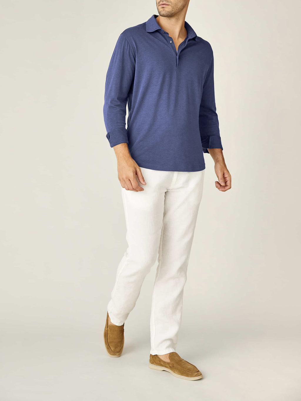 A model wears the Amalfi Silk-Cotton Polo Shirt in Ocean Blue with white linen trousers and brown suede loafers.