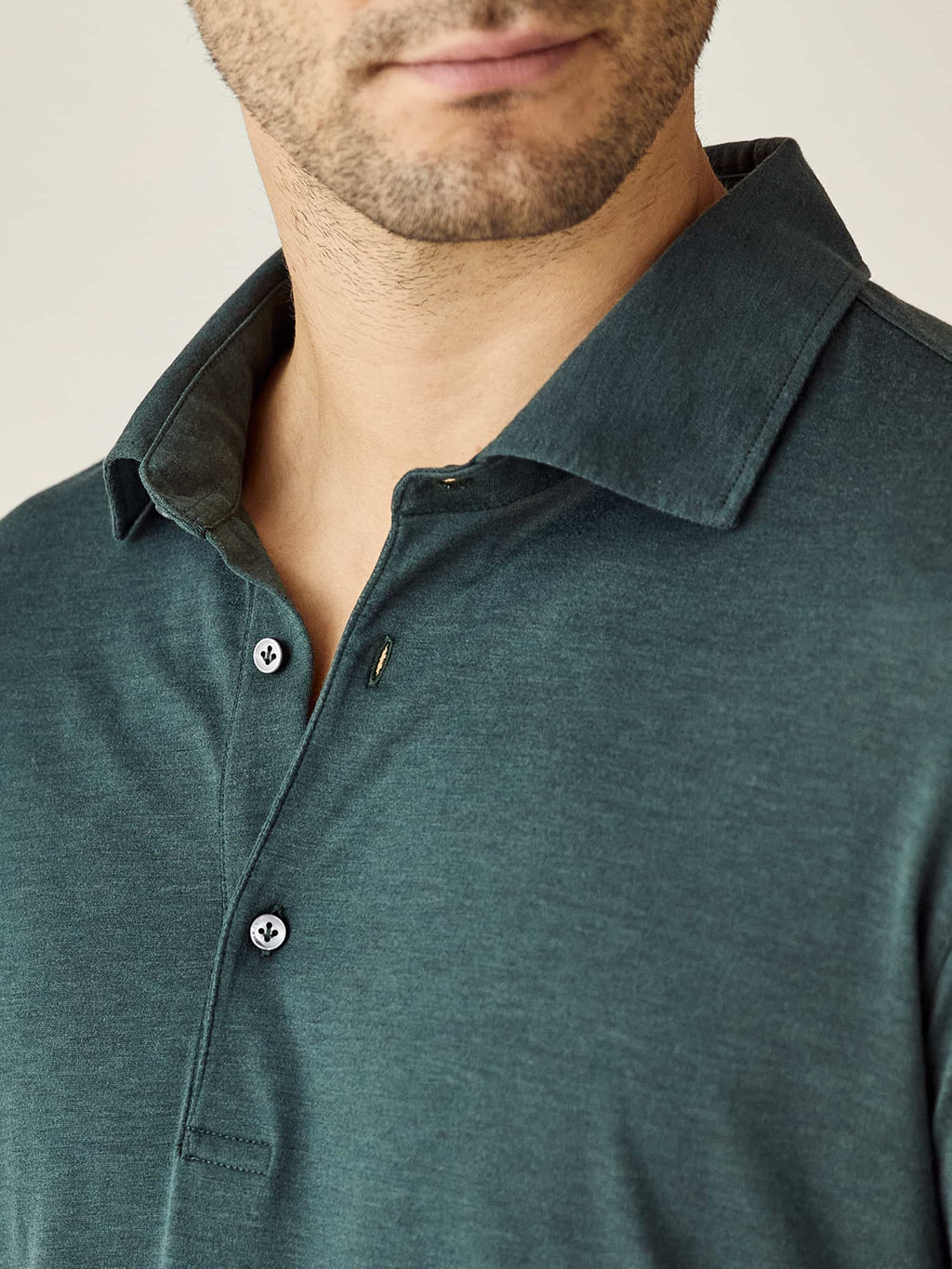 Close-up detail of the collar and mother-of-pearl buttons on the Amalfi Silk-Cotton Polo Shirt in Emerald Green.