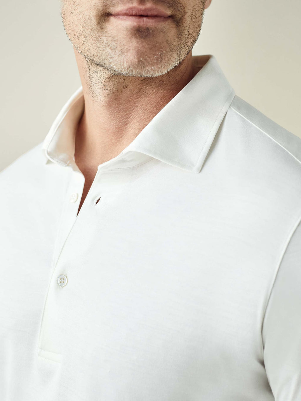 Close-up of the white Amalfi Silk-Cotton Polo Shirt, showing the soft fabric, collar, and mother of pearl buttons.