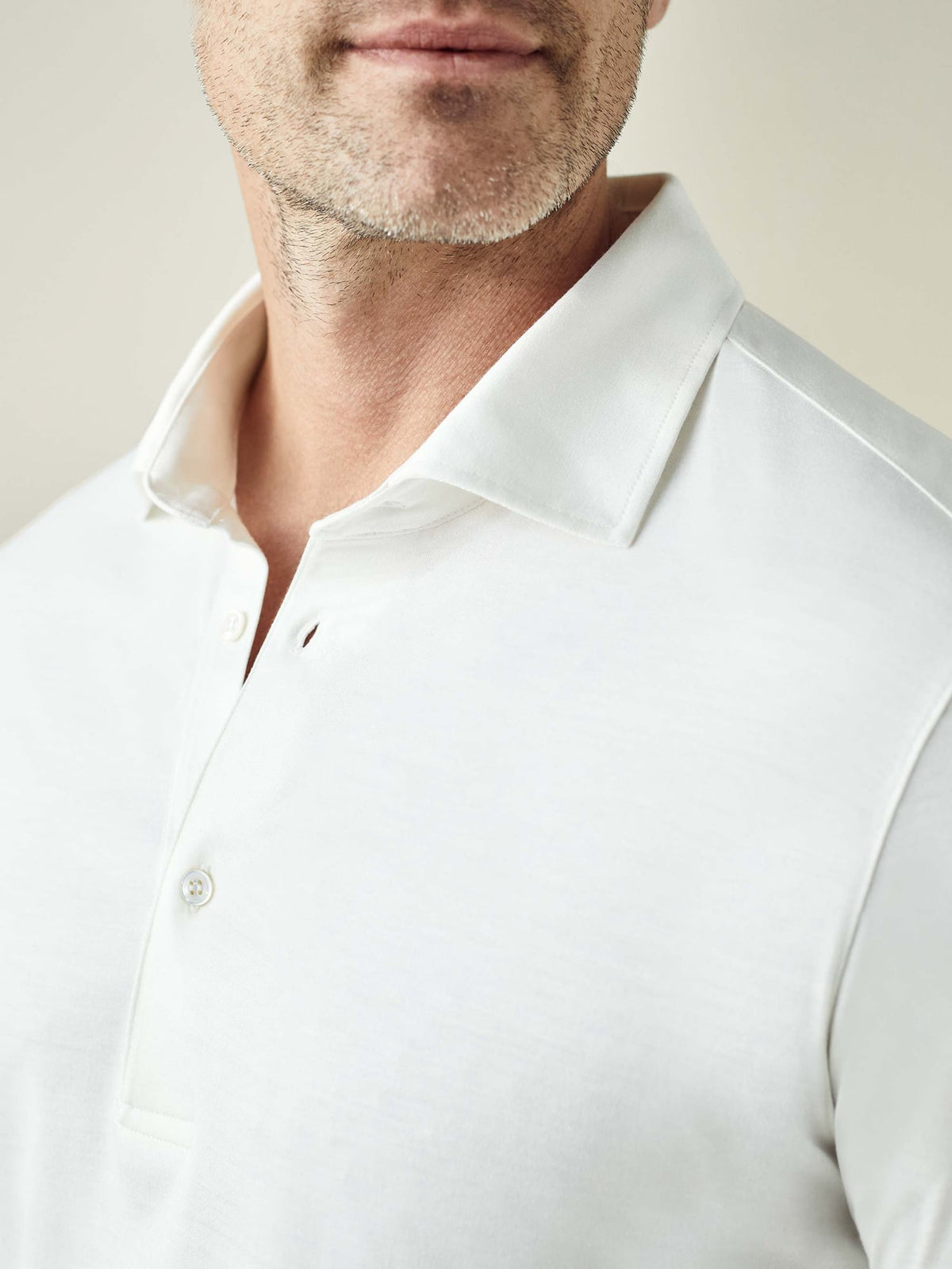 Close-up of the white Amalfi Silk-Cotton Polo Shirt, showing the soft fabric, collar, and mother of pearl buttons.