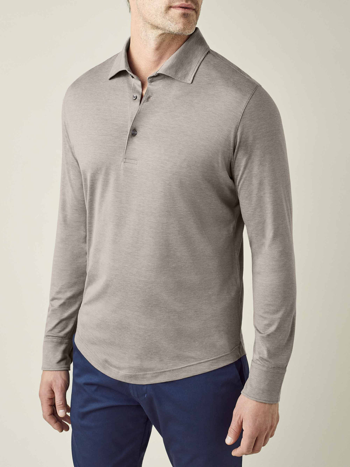 Front three-quarter view of a model wearing the Amalfi Silk-Cotton Polo Shirt in Nocciola Brown with navy trousers.